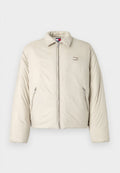 Beige Daunenjacke mit Stehkragen, Frontreißverschluss und zwei Seitentaschen. Mit einem Logopatch auf der linken Brust.