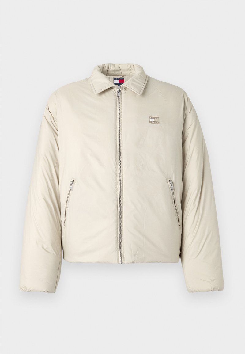 Beige Daunenjacke mit Stehkragen, Frontreißverschluss und zwei Seitentaschen. Mit einem Logopatch auf der linken Brust.