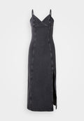 Schwarzes Denim-Maxi-Kleid mit Spaghettiträgern, V-Ausschnitt und dekorativen Nieten entlang des Oberteils. Mit einem seitlichen Schlitz und taillierter Silhouette.