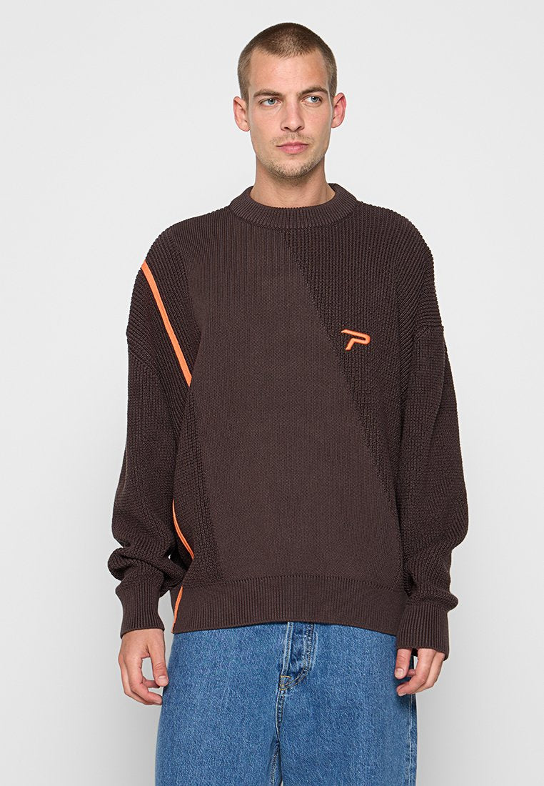 Brauner gestrickter Pullover mit rundem Ausschnitt, verziert mit einem orangen diagonalen Streifen und Logo-Detail auf der Brust. Lockere Passform, strukturierter Stoff.