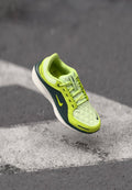 Limettengrüne Sneaker mit gestepptem Obermaterial, dunkelgrünen Akzenten, weißer Sohle und sichtbarem schwarzem Nike-Swoosh; verfügt über ein schnürbares Design und eine strukturierte Oberfläche.