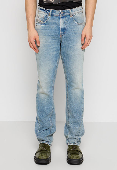 Helles blaues Denim-Jeans mit lockerer Passform, ausgewaschenem Finish, fünf Taschen und geradem Bein, gezeigt mit grünen Schuhen.