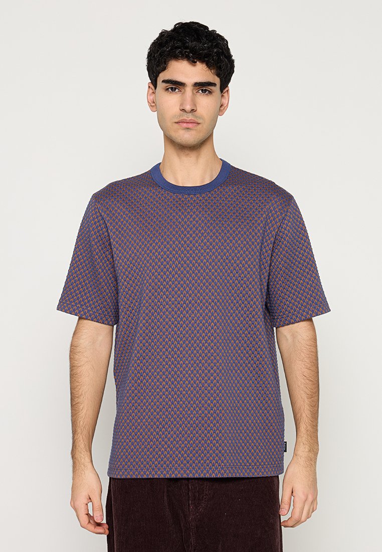 Kurzärmliges T-Shirt in Lila mit einem Rautenmuster in Orange. Verfügt über einen runden Ausschnitt und eine lockere Passform. Hergestellt aus einem strukturierten Stoff.