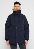 Lächelnder Mann, der eine marineblaue Winterparka mit einer fellbesetzten Kapuze, Knopf- und Reißverschluss sowie vorderen Taschen trägt, vor einem schlichten Hintergrund.