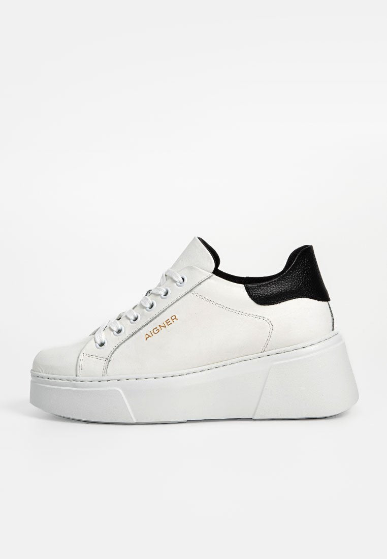 Weiße Leder Sneaker mit schwarzer Fersenakzent, dicker Plateausohle, silbernen Ösen und goldenen Logo-Details an der Seite. Glatte Textur.