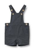 Dunkelgraue Latzshorts aus Stoff mit verstellbaren Trägern, Holzknöpfen, Fronttaschen und Druckknöpfen am Saum.