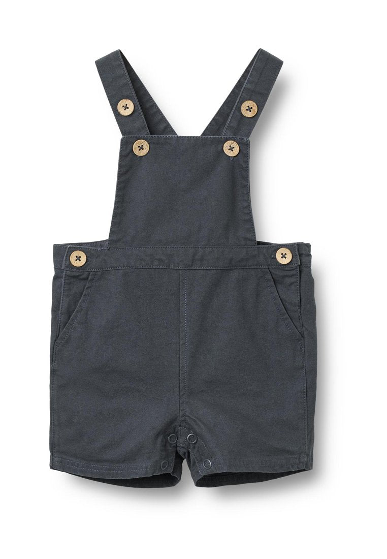 Dunkelgraue Latzshorts aus Stoff mit verstellbaren Trägern, Holzknöpfen, Fronttaschen und Druckknöpfen am Saum.