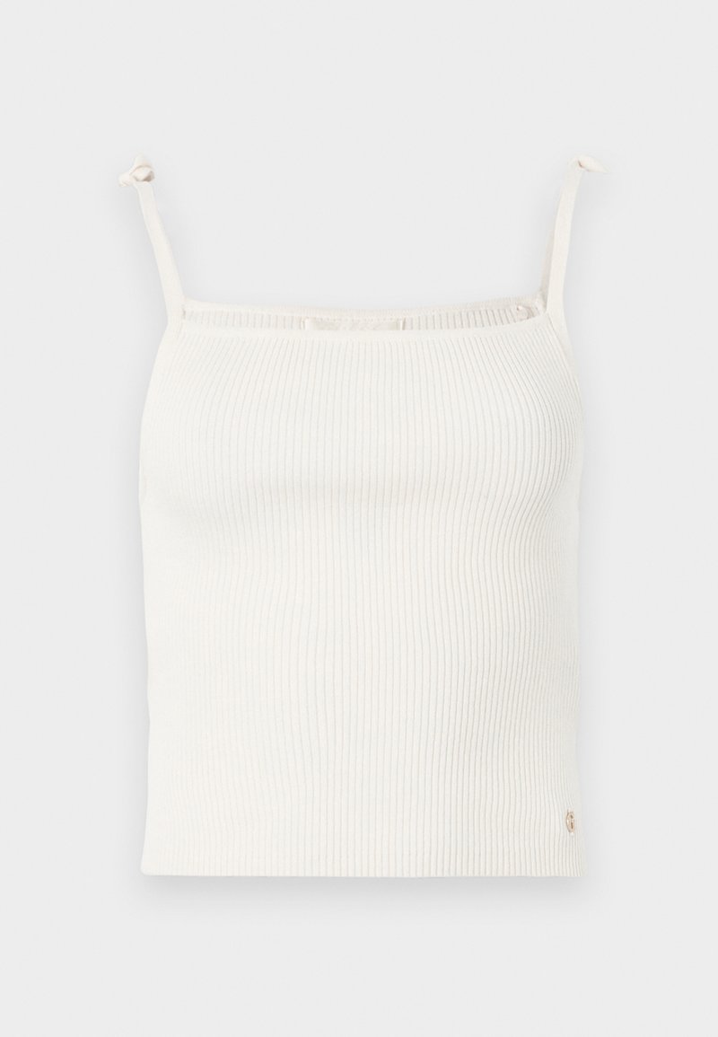 Rippentop in Creme mit dünnen, verstellbaren Trägern und einem kleinen Logo-Akzent am Saum. Weicher Stoff. Taillierte Passform.