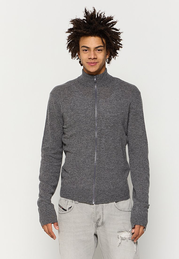 Grauer Reißverschluss-Pullover mit hohem Kragen, schlanker Passform, gerippten Bündchen und Saum. Hergestellt aus einer weichen Textur, kombiniert mit hellgrauen, verwaschenen Jeans.