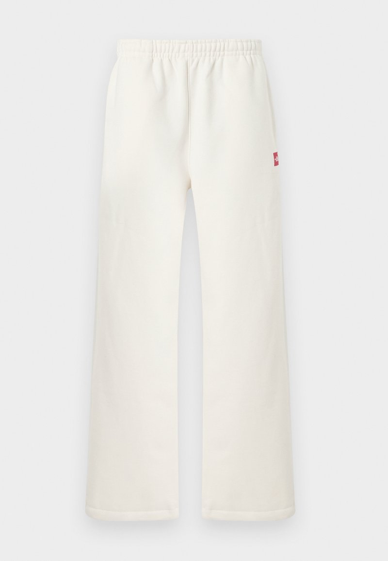 Off-white gerade geschnittene Hose mit elastischem Bund und kleinem rotem Fleck auf der rechten Seite, vor einem schlichten hellen Hintergrund präsentiert.
