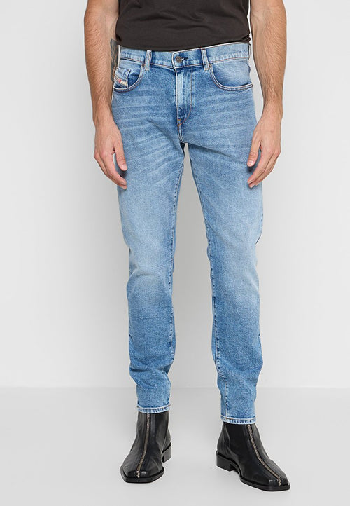 Hellblaue Jeans aus Denim mit Slim-Fit, die subtile Verwaschungen, fünf Taschen und Schlaufen für einen Gürtel aufweisen. Getragen mit schwarzen Reißverschluss-Stiefeletten.