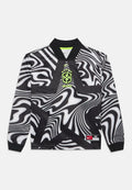 Langarmshirt mit schwarz-weißen, wellenförmigen Streifen, neon-gelbem Brasilien-Wappen, Nike-Logo und einem Größenetikett am Saum. Keine Personen sichtbar.