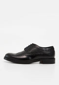 Schwarzer Lederschnürschuh mit Brogue-Design, perforierten Ziermustern und schwarzen Schnürsenkeln, von der Außenseite vor weißem Hintergrund gezeigt.