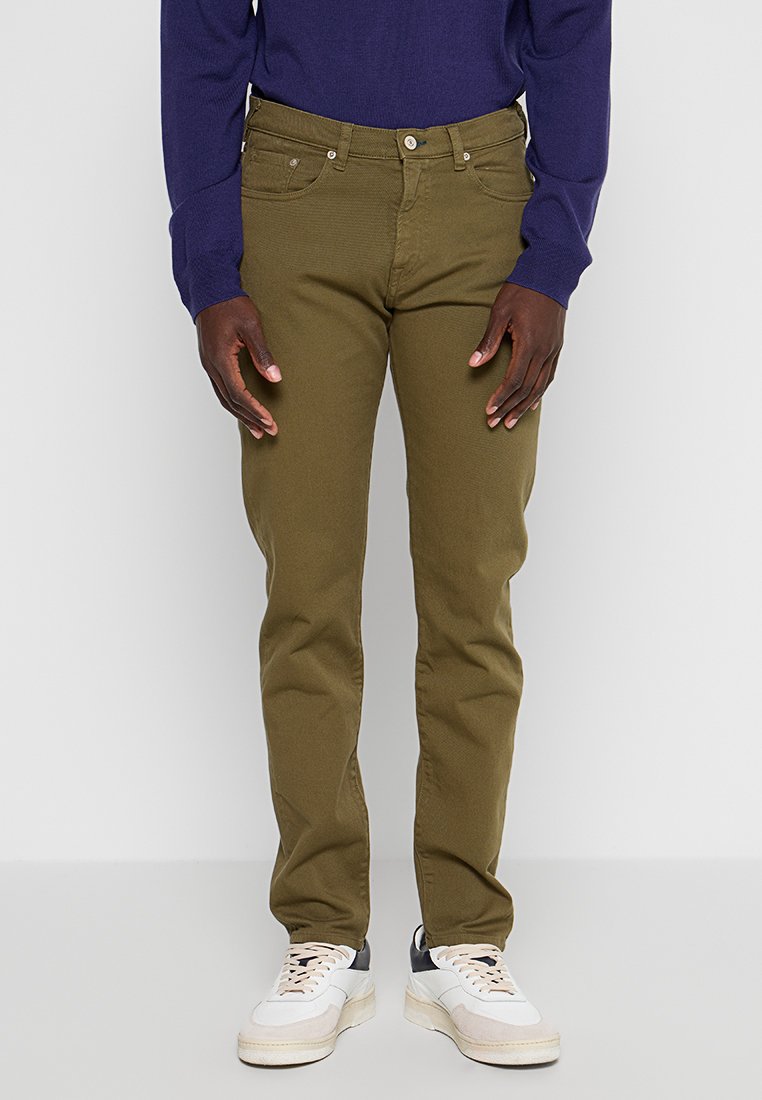 Olivgrüne Baumwoll-Chinos mit schmaler Passform. Verfügt über fünf Taschen, eine Gürtelschlaufe und einen Knopfverschluss. Kombiniert mit weißen und grauen Sneakers.