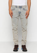 Ausgebleichte hellblaue Jeans mit geradem Schnitt, fünf Taschen und leichten Gebrauchsspuren an den Knien. Getragen mit dunklen Sneakers.