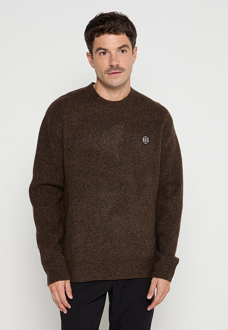 Brauner Wollpullover mit langen Ärmeln, Rundhalsausschnitt und einem kleinen runden Logo auf der Brust. Weiche Textur und lässige Passform.