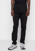 Person, der schwarze Cargo-Hosen mit Klappentaschen und silberne Sport-Sneaker trägt, vor einem schlichten weißen Hintergrund steht.