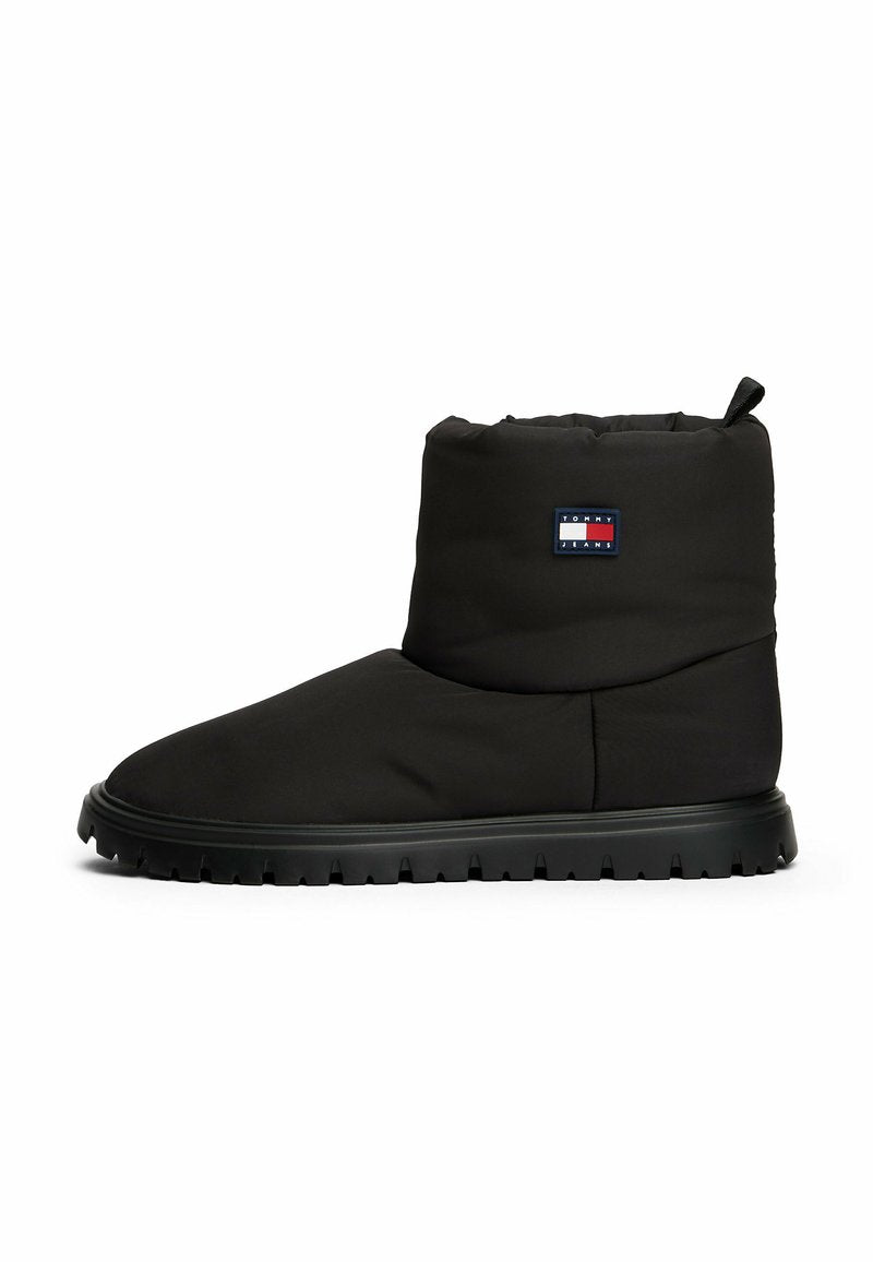 Schwarze gepolsterte Knöchelstiefel mit runder Spitze und gerillter Sohle. Verfügt über ein Logo-Patch an der Außenseite und eine Zuglasche am oberen Ende.