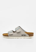 Ein einzelner beiger Slide-Sandal mit zwei verstellbaren silbernen Schnallen, Korkfußbett, weißer Sohle und "BAYTON" Logo mit Anker an der Seite.