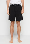 Schwarze Baumwollshorts mit einem elastischen Bund, der das "DIESEL"-Logo in Weiß zeigt. Das Design ist locker und minimalistisch geschnitten.