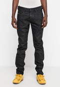 Schwarze Denim-Jeans mit slim fit, mit einem Fünf-Taschen-Design, betonten Nähten und einer glatten Textur. Kombiniert mit gelben Sportschuhen.