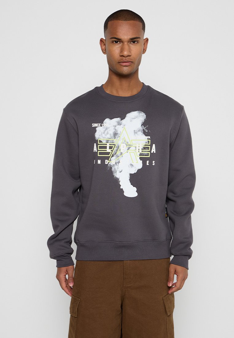 Grauer Pullover aus Baumwollmischung, der ein grafisches Design mit gelben Akzenten und einem Sternmotiv auf der Vorderseite zeigt. Gerippte Bündchen und Saum.
