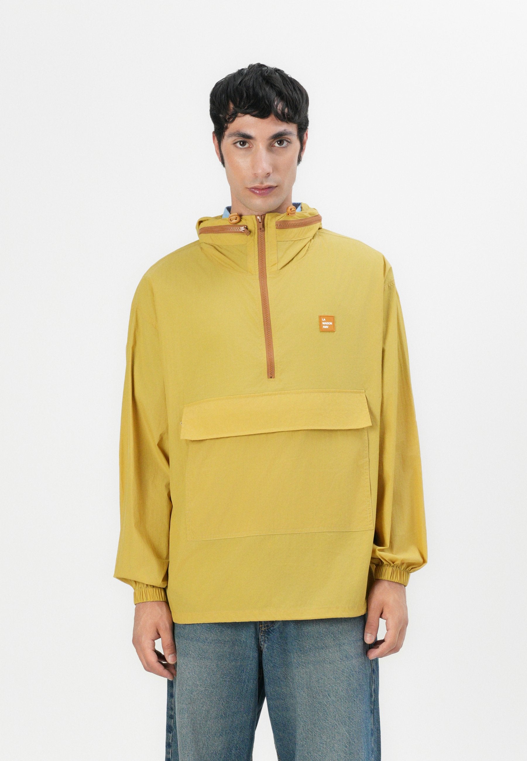 Gelbe leichte Jacke mit einer Fronttasche, halbem Reißverschluss, elastischen Bündchen und einer Kordelzugkapuze. Glatte Textur, minimalistisches Design.