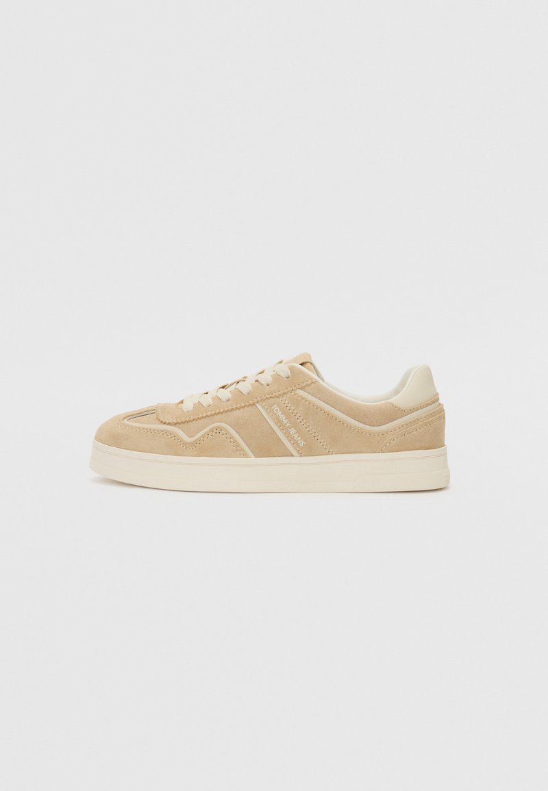 Beige Wildlederschuhe mit einem niedrigen Design, ausgestattet mit cremefarbenen Akzenten und einer strukturierten Sohle. Dezente Nähdetails und Logo an der Seite.