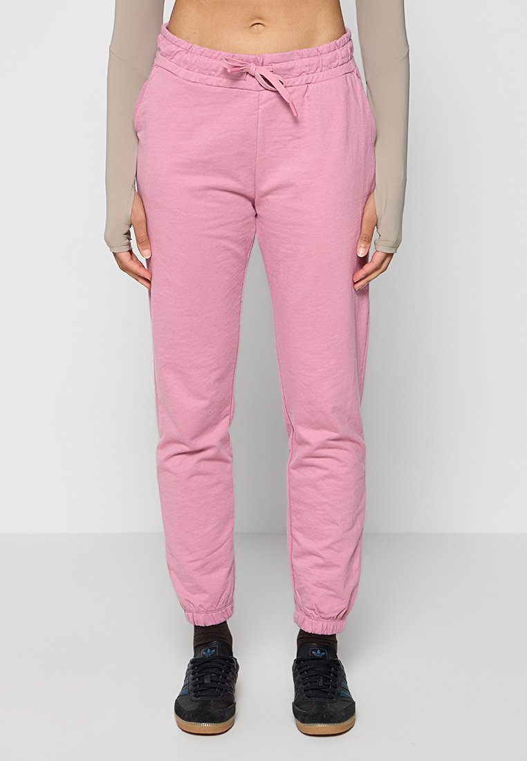 Helle rosa Jogginghosen mit elastischem Bund und Kordelzug. Sie verfügen über elastische Bündchen an den Knöcheln und eine weiche, glatte Textur.