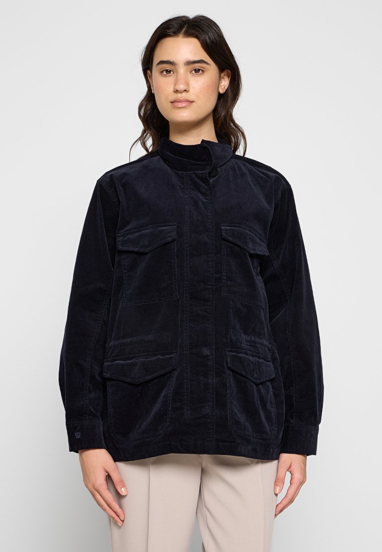 Marineblaues Cord-Jacket mit hohem Kragen, zwei Fronttaschen und geradem Schnitt. Strukturiertes Gewebe mit sauberem Finish.