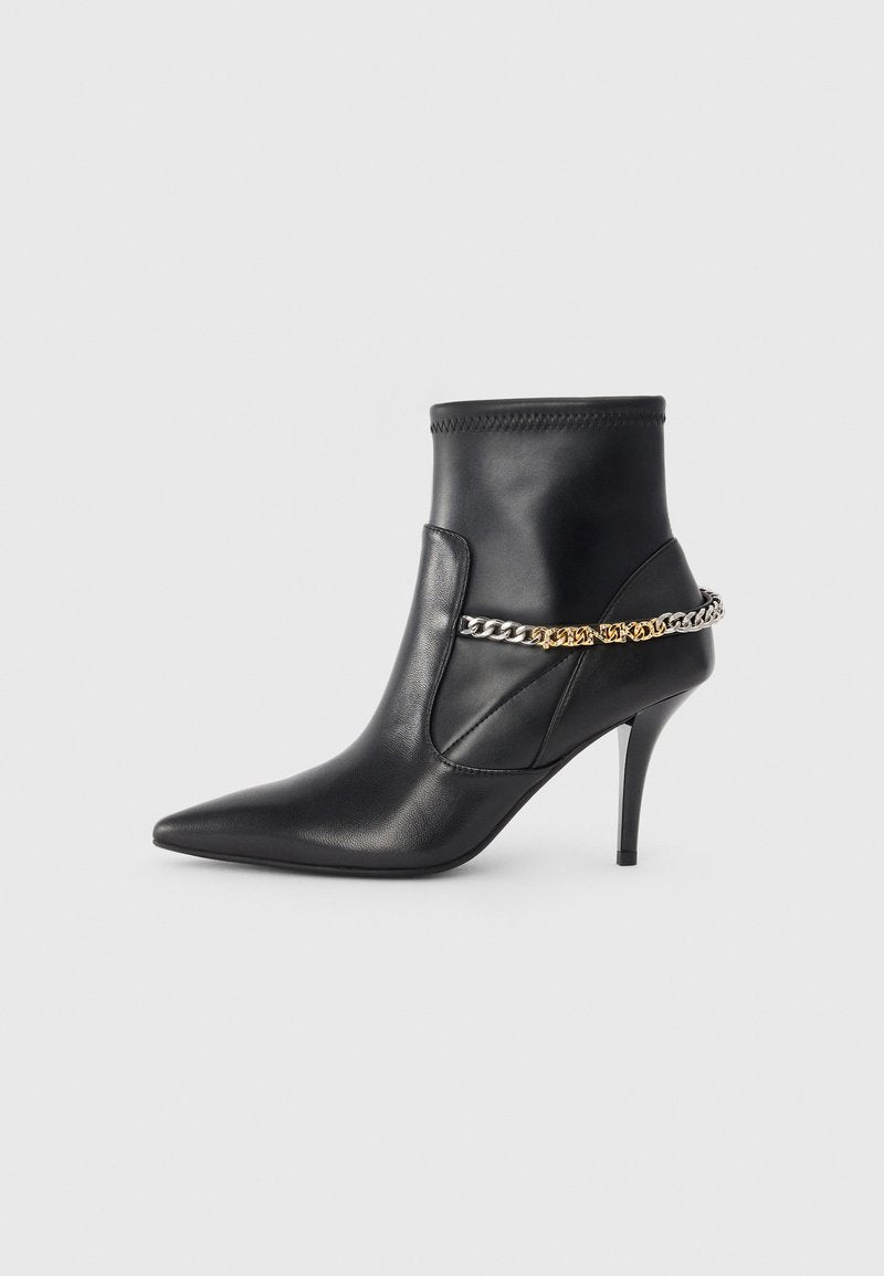 Schwarzer Lederknöchelstiefel mit spitzem Zeh, hohem Stiletto-Absatz und dekorativem gold- und silberfarbenem Kettenakzent um den Knöchel.