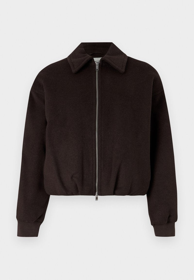 Schwarze, kurz geschnittene Jacke mit Reißverschluss, die einen Kragen und gerippte Bündchen hat, aus einem weichen, strukturierten Stoff gefertigt.