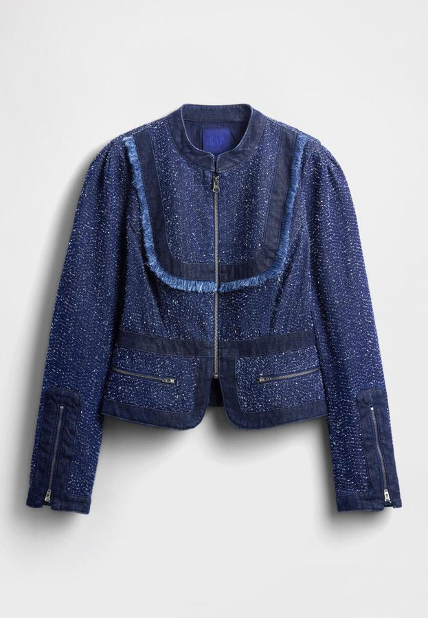 Dunkelblaue Jeansjacke mit strukturierter Stoffqualität, Fransen entlang des Kragens, Reißverschluss vorne und zwei Fronttaschen mit Reißverschlüssen.