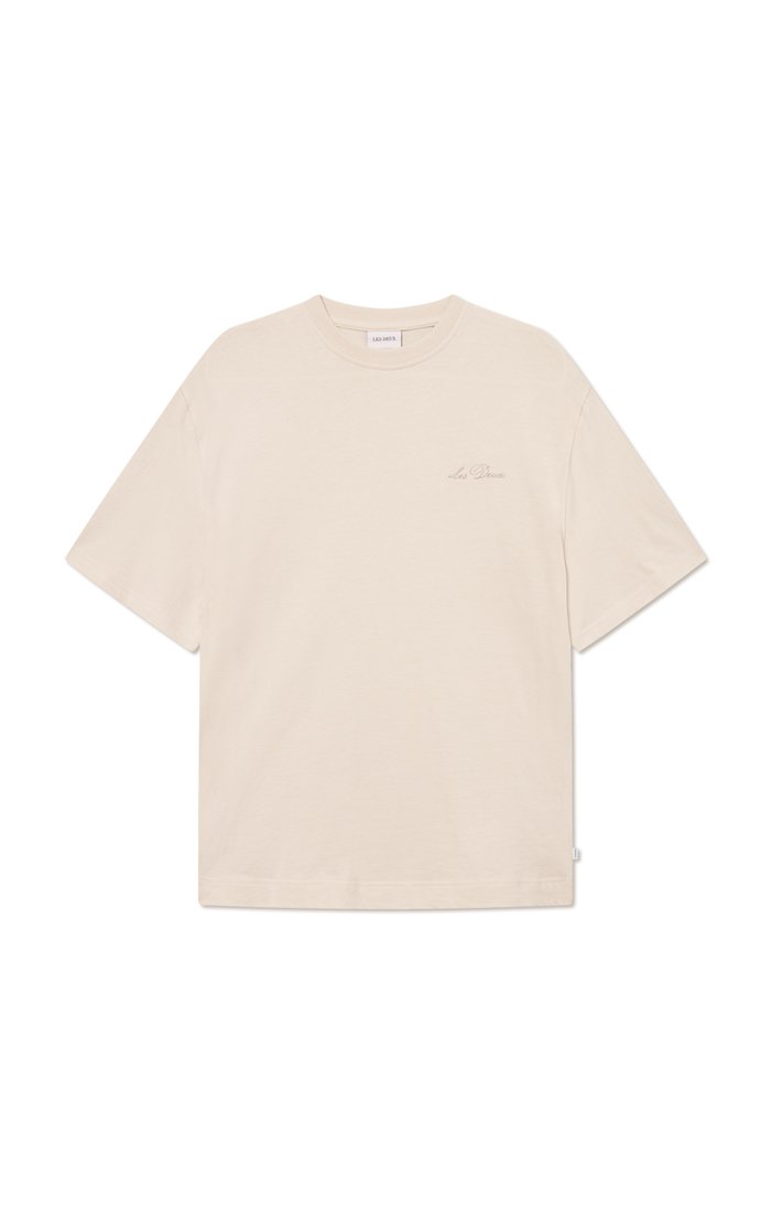 Beige Baumwoll-T-Shirt mit lockerer Passform, kurzen Ärmeln, rundem Halsauschnitt und subtiler Branding auf der Brust. Glatte Textur, minimalistisches Design.
