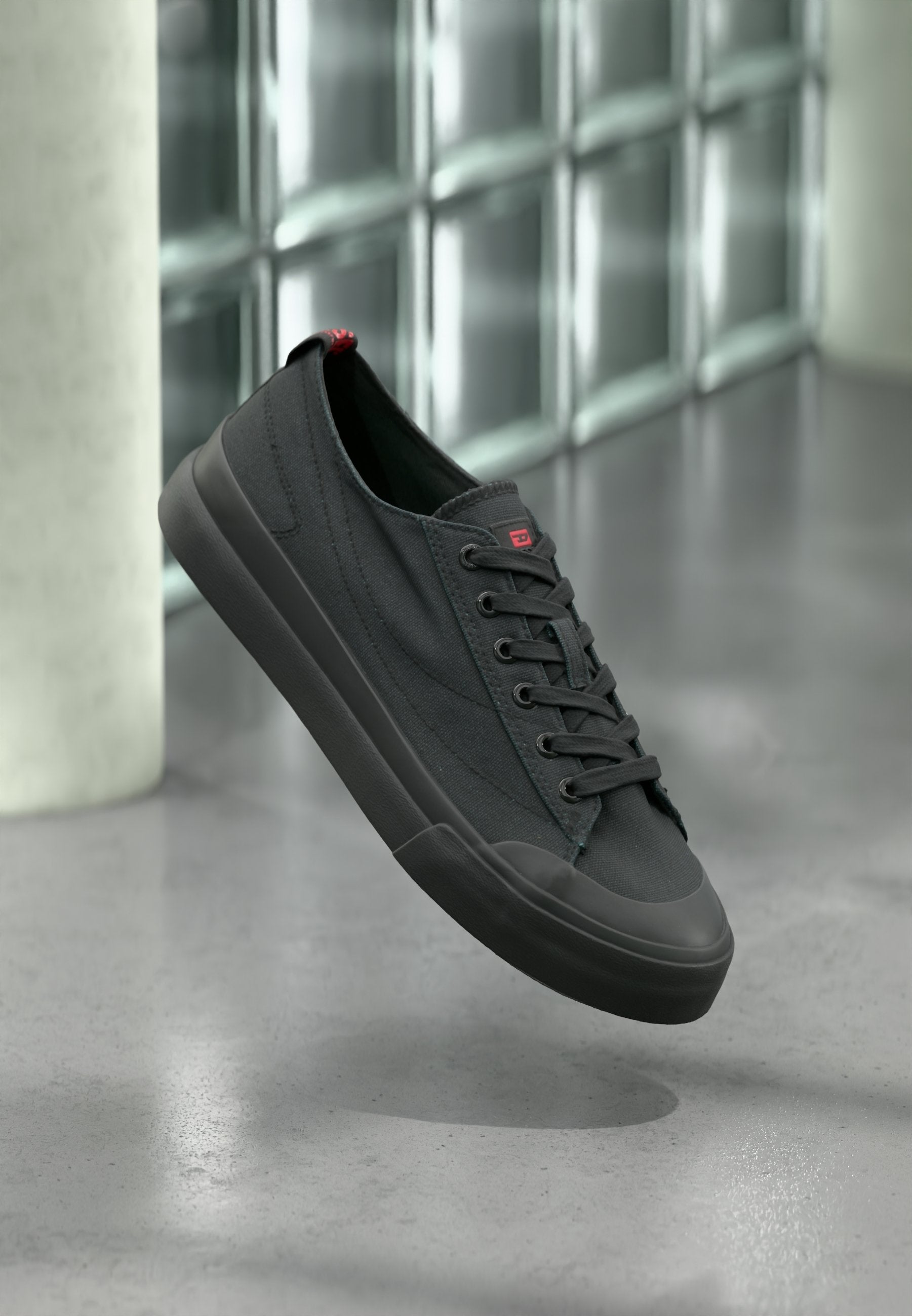 Schwarze Leinwand-Sneaker mit Gummisohle, runder Zehenpartie und Schnürdesign. Verfügt über ein kleines rotes Logo auf der Zunge und seitliche Nahtdetails.