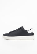 Schwarze Ledersneaker mit weißen Akzenten, flache Sohle, runde Zehenform und sechs Paar Ösen für Schnürsenkel. Glatte Textur, minimalistisches Design.