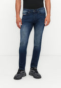 Jeans aus Denim in dunkelblauem Waschungen, schmaler Schnitt mit verblassten Details, Fünf-Taschen-Design, Metallknopfverschluss, kombiniert mit schwarzen Sportschuhen.