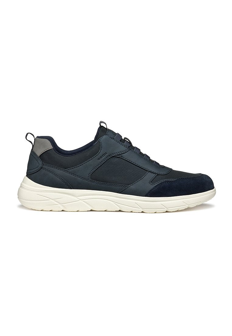 Marineblauer Sportschuh mit einer Mischung aus glattem Leder und Mesh-Obermaterial, rundem Zehenbereich, strukturierten Akzenten und einer weißen, gepolsterten Außensohle.