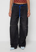 Schwarze, weit geschnittene Cargo-Jeans mit blauem Kordelzug am Bund, Seitentaschen, kombiniert mit hellblauen, spitzen High Heels und einem kurz geschnittenen roten Top mit Muster.