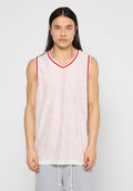 Junge Person mit langen, dunklen Haaren in einem weißen, ärmellosen Sporttrikot aus Netzstoff mit roten Akzenten und hellgrauen Hosen.