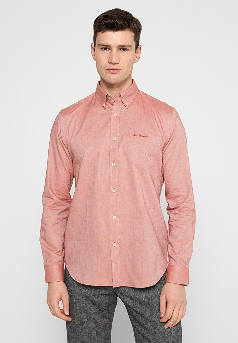 Langärmliges Button-Up-Hemd aus hellrotem strukturiertem Stoff, mit einer Tasche und gesticktem Logo auf der Brust. Klassisches Kragenlayout.