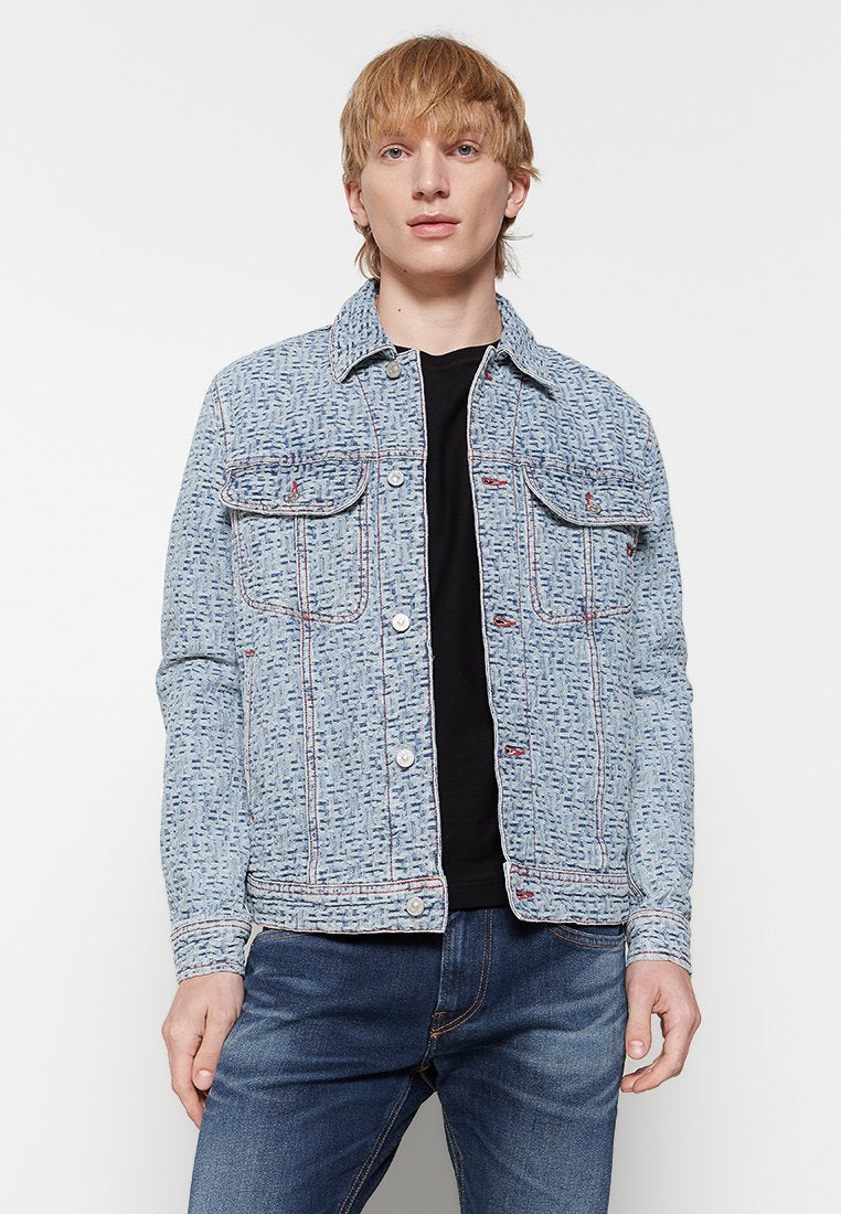 Jeansjacke mit einem hellblauen, strukturierten Muster, zwei Brusttaschen, Knopfverschluss und roten Nähakzenten, kombiniert mit einem schwarzen Hemd darunter.