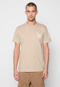 Beige Baumwoll-T-Shirt mit kurzen Ärmeln und Rundhalsausschnitt, mit einem kleinen weißen Logo auf der linken Brust. Glatte Textur.