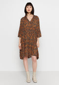 Schwarz-orange-blumiges Kleid mit Dreiviertelärmeln, knielangen Rüschen, V-Ausschnitt und fließender Silhouette. Tragen mit beigen KnöchelStiefeln.
