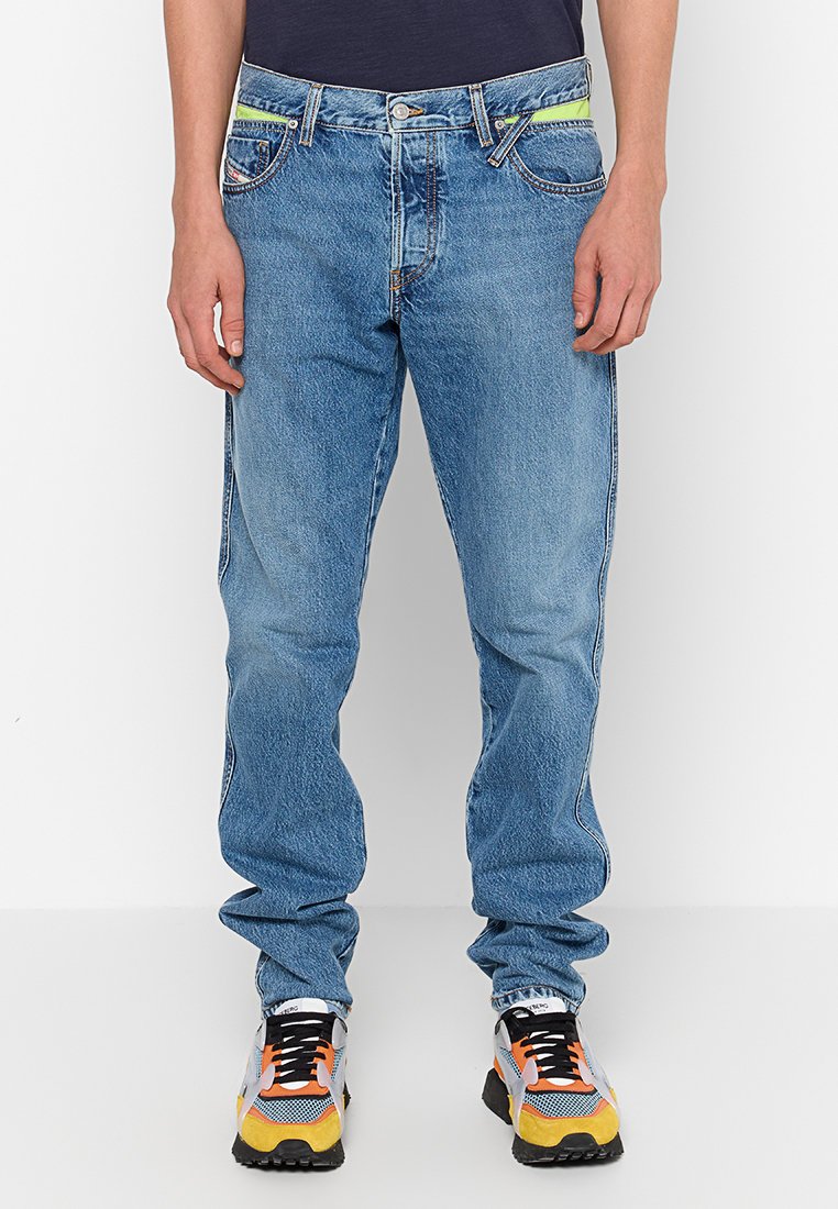 Hellblaue Jeans im lässigen Schnitt, mit kontrastierenden gelben Akzenten an den Taschen und einem klassischen Knopfverschluss.