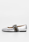 Silberner flacher Schuh mit schwarzem Riemen, verziert mit Perlen, Strasssteinen und einer kleinen goldenen Schnalle, vor weißem Hintergrund.