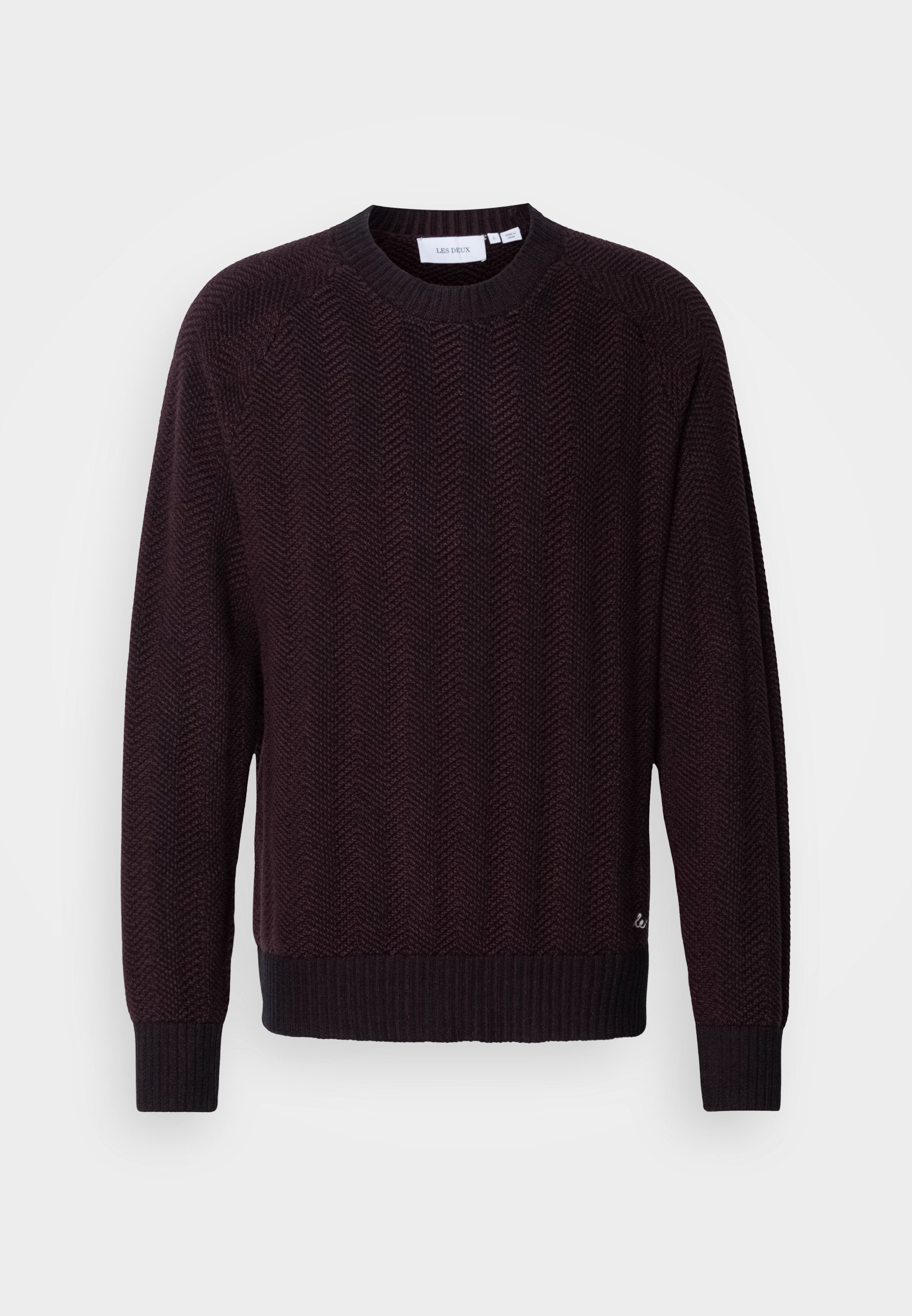 Dunkelmaroon gestrickter Pullover mit einem strukturierten Fischgrätenmuster, rundem Ausschnitt und gerippten Bündchen sowie Saum. Subtiler Logo-Detail am unteren Rand.