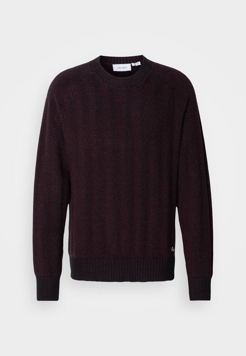 Dunkelmaroon gestrickter Pullover mit einem strukturierten Fischgrätenmuster, rundem Ausschnitt und gerippten Bündchen sowie Saum. Subtiler Logo-Detail am unteren Rand.