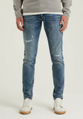 Dünne blaue Jeans mit einer mittleren Waschung und verwaschenen Details. Kombiniert mit weißen Turnschuhen, die einen lässigen Stil zeigen.