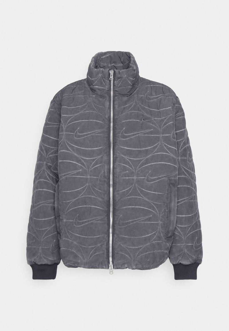 Graue, gesteppte Pufferjacke mit hohem Kragen, Frontreißverschluss und elastischen Bündchen. Sie verfügt über das eingeprägte Nike-Logo und ein gewelltes Linienmuster.